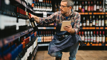 Salesman with digital tablet taking stock of wine