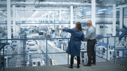 Business leaders in a manufacturing facility discussing mergers and acquisitions